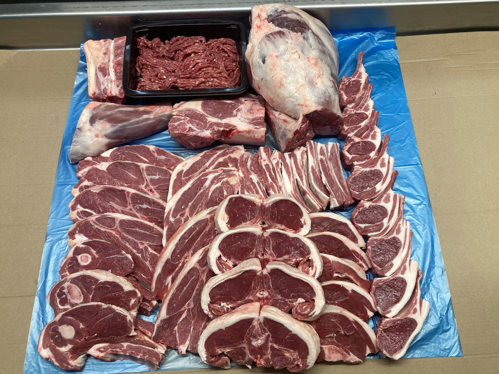 Assorted cuts of raw meat on a blue plastic sheet. Half Lamb